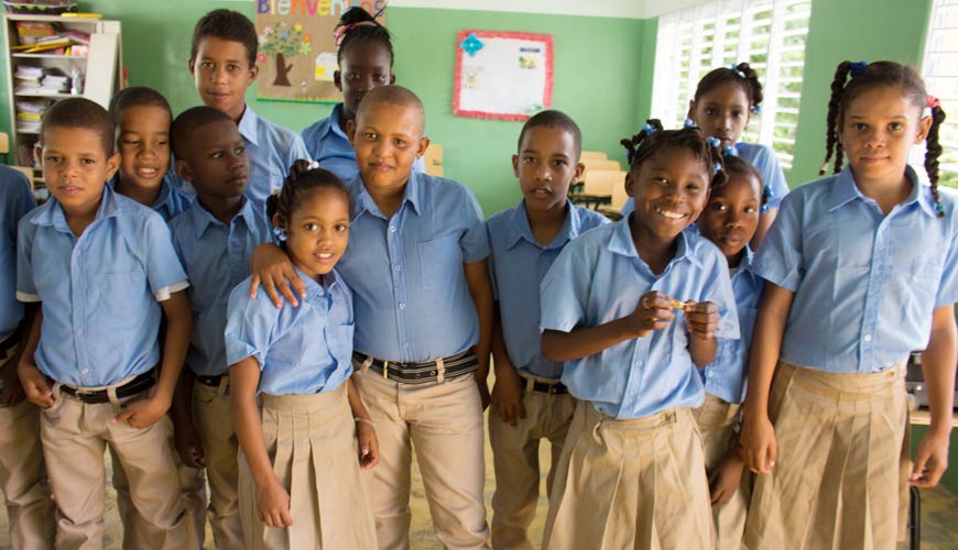 A group of children in blue shirts and tan pants.