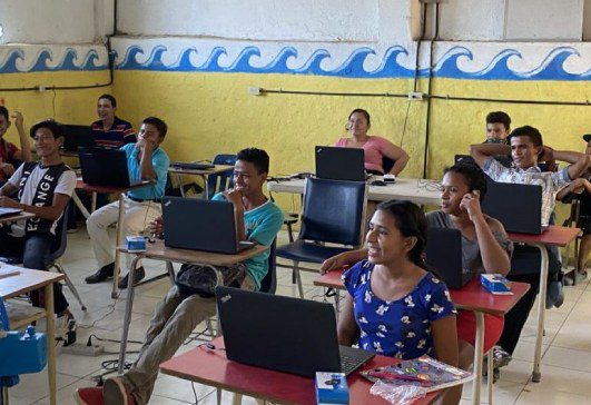 A group of people sitting at tables with laptops.