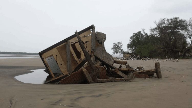 A house that is falling down on the beach.