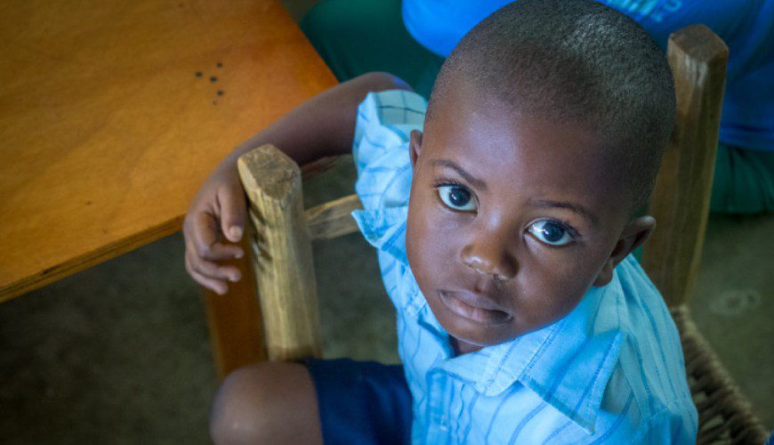 A young boy sitting on the floor holding a wooden block.