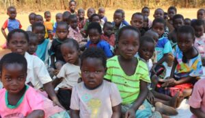 A group of children sitting in the grass.