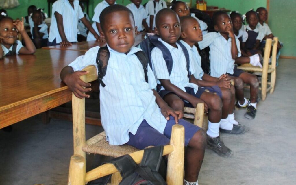 A group of children sitting in chairs at a table.